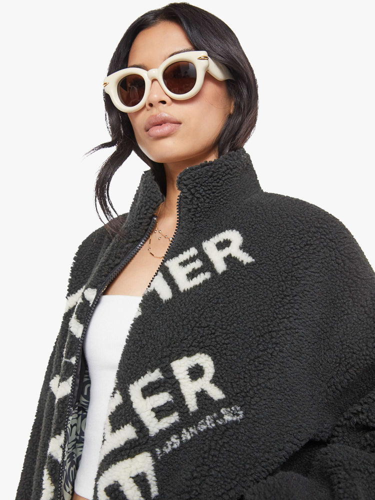 Close up view of a woman in a reversible fleece jacket with a stacked collar, zip closure, patch pocket at the chest, slightly dropped shoulders and a loose fit.