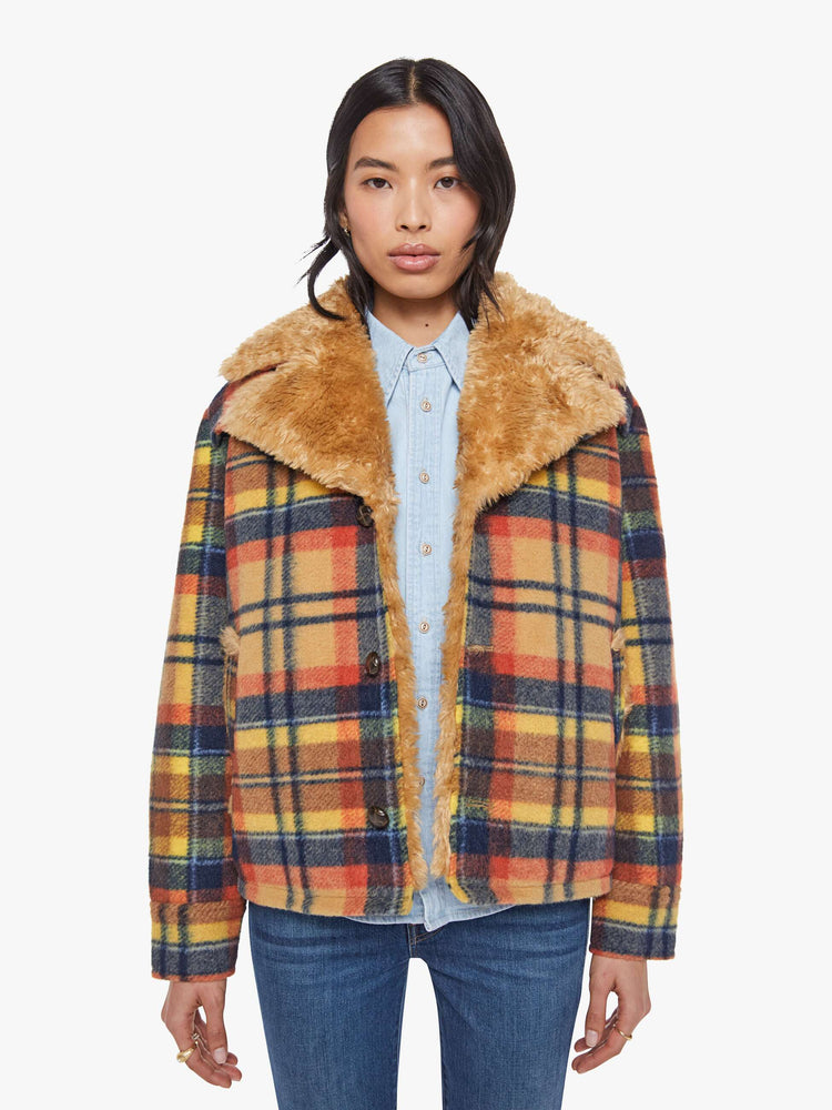 Front view of a woman in yellow, orange, and navy plaid boxy jacket with an oversized notched collar, buttons down the front and a loose fit.