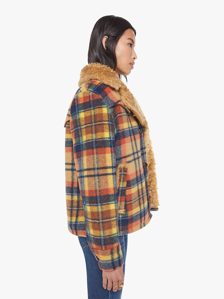 Side view of a woman in yellow, orange, and navy plaid boxy jacket with an oversized notched collar, buttons down the front and a loose fit.