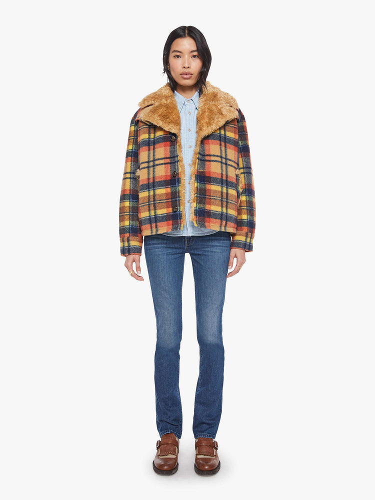 Full body view of a woman in yellow, orange, and navy plaid boxy jacket with an oversized notched collar, buttons down the front and a loose fit.