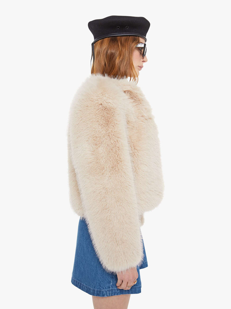 Side view of a light pink faux fur  cropped jacket with a crewneck and boxy fit. 