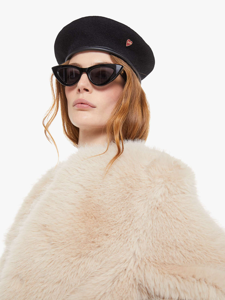 Close up view of a light pink faux fur  cropped jacket with a crewneck and boxy fit. 