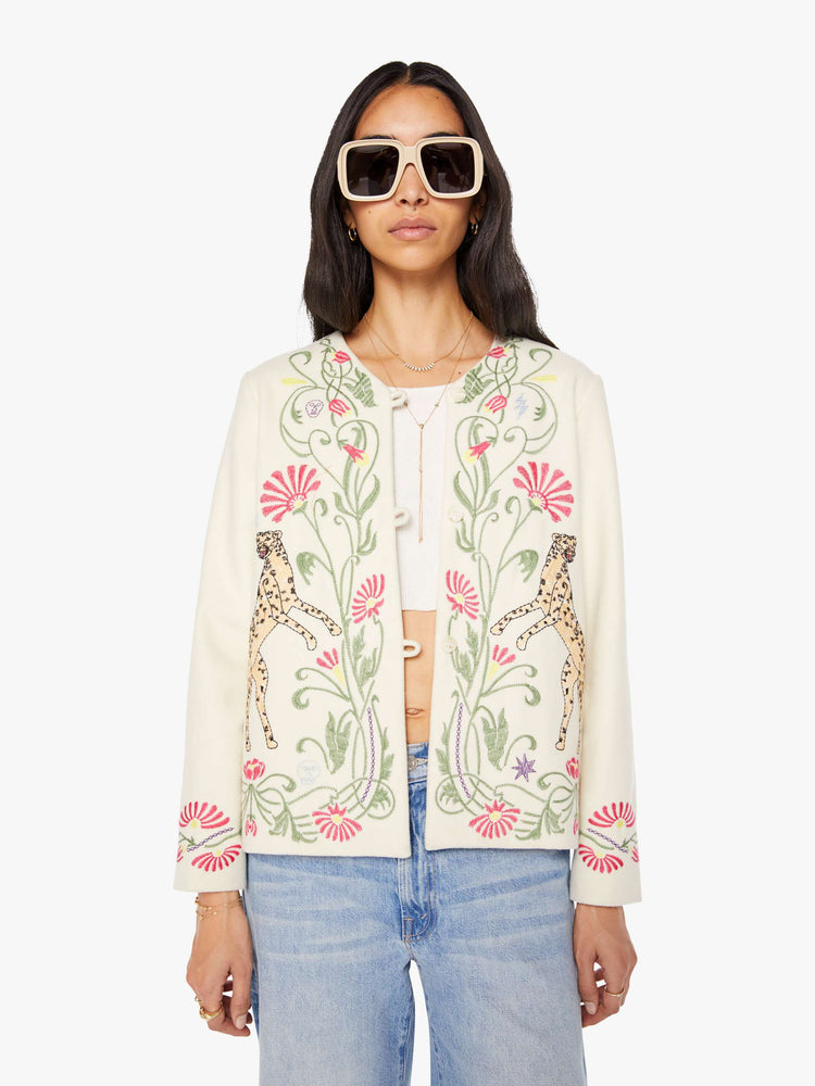 Front view of a woman in creamy off-white with floral details cheetahs V-neck jacket with buttons down the front and a loose, boxy fit.