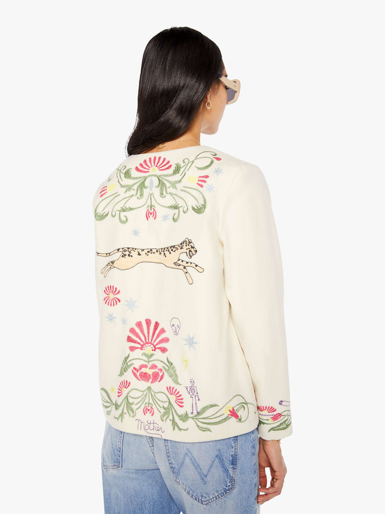 Back view of a woman in creamy off-white with floral details cheetahs V-neck jacket with buttons down the front and a loose, boxy fit.