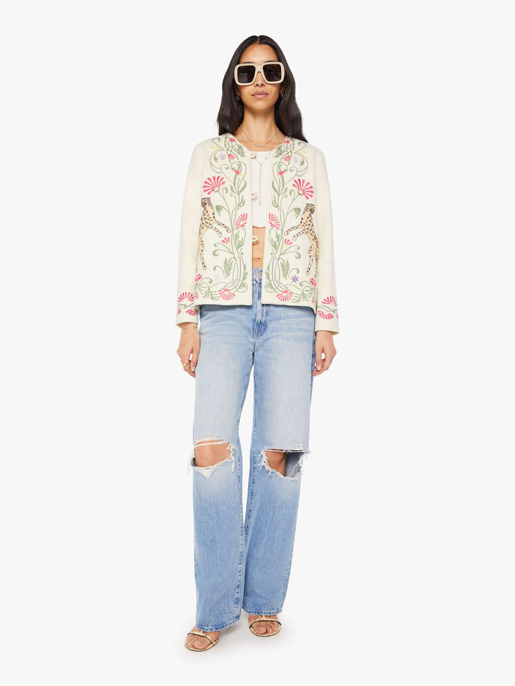 Full body view of a woman in creamy off-white with floral details cheetahs V-neck jacket with buttons down the front and a loose, boxy fit.