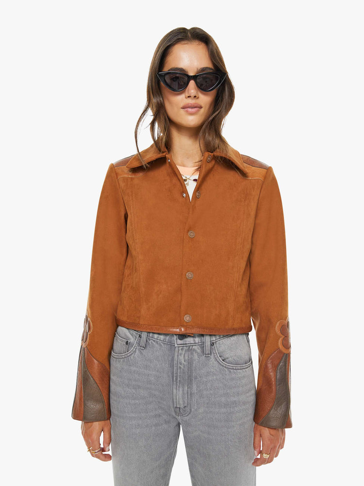 Front view of a woman in a dark caramel with faux leather patchwork details jacket across the back and sleeves and a colorful printed lining.