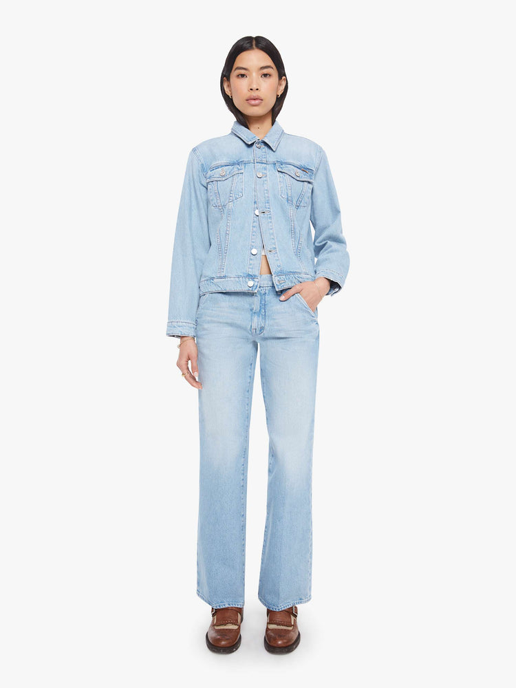 Full body view of a woman in a light blue denim jacket with front patch pockets and a slightly cropped fit.