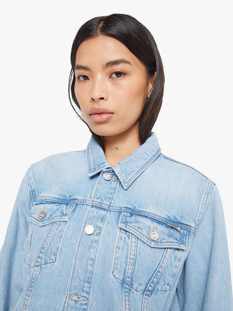 Close up view of a woman in a light blue denim jacket with front patch pockets and a slightly cropped fit.
