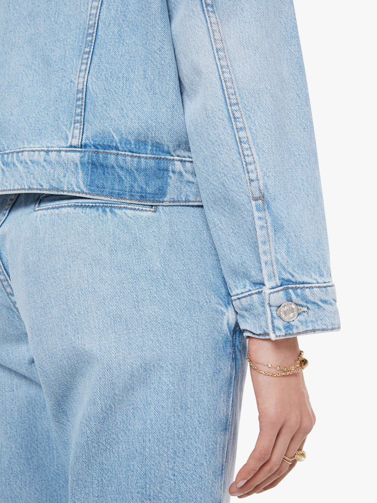 Swatch view of a woman in a light blue denim jacket with front patch pockets and a slightly cropped fit.