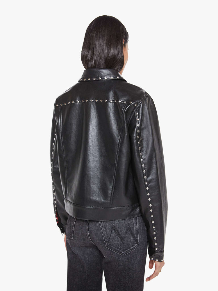 Back view of a woman in a black faux leather  classic button-up jacket with front patch pockets, drop shoulders and a boxy fit. 
