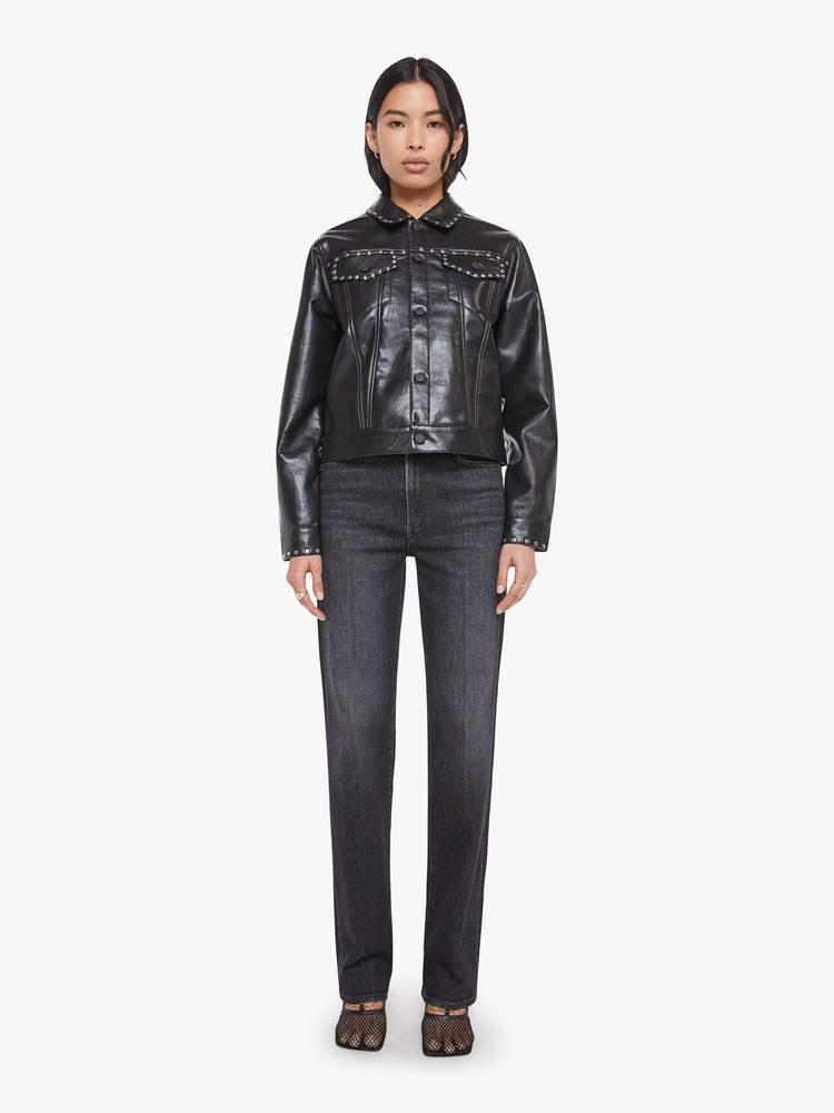 Full body view of a woman in a black faux leather  classic button-up jacket with front patch pockets, drop shoulders and a boxy fit. 