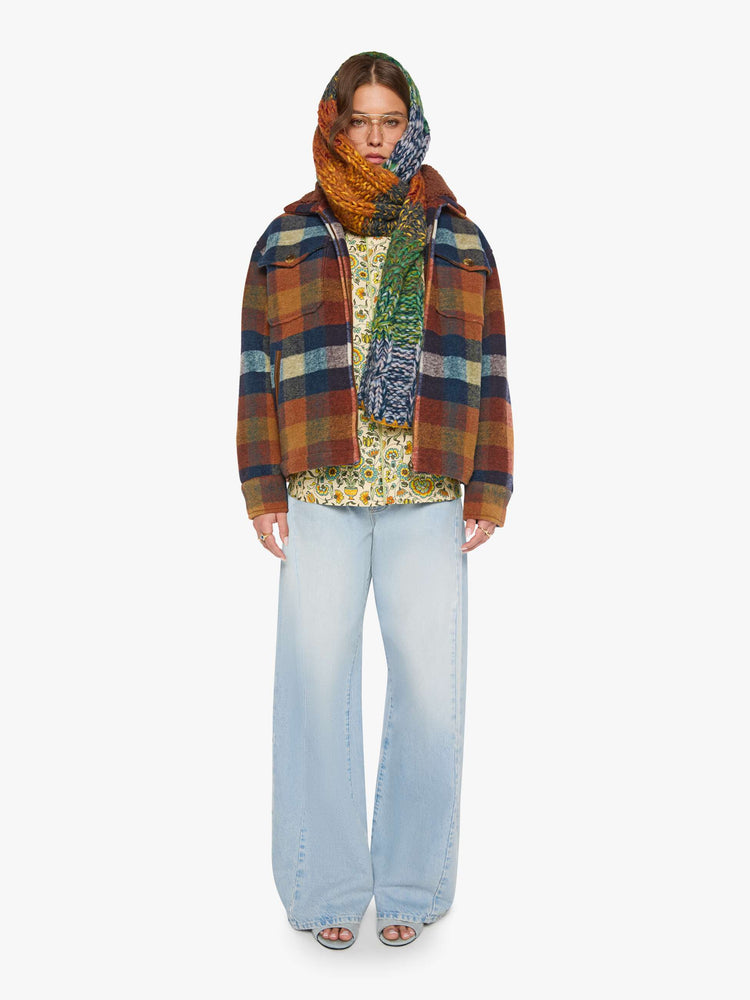 Full body view of a woman in a brick red, navy, yellow and white plaid print with fuzzy faux-sherpa lining on the collared jacket with front patch pockets, a zip closure, drop shoulders and an oversized fit.