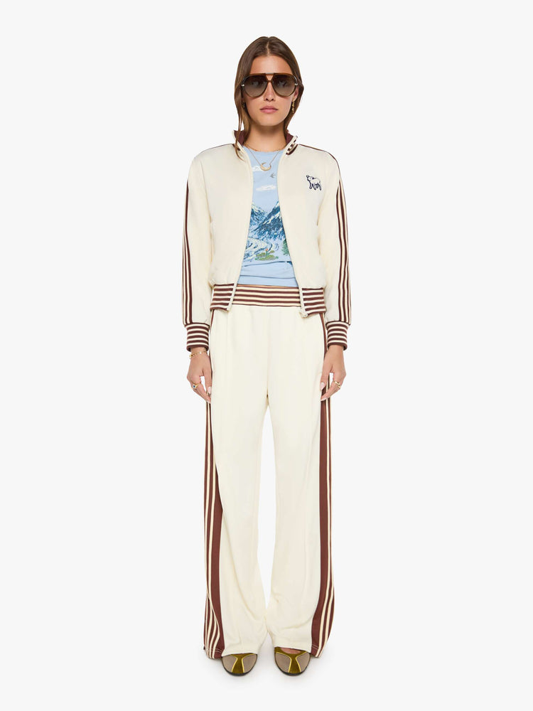 full body view of a woman in an off-white the jacket features brown and white stripes down the sleeves and at the hems and a fuzzy lamb patch on the chest.