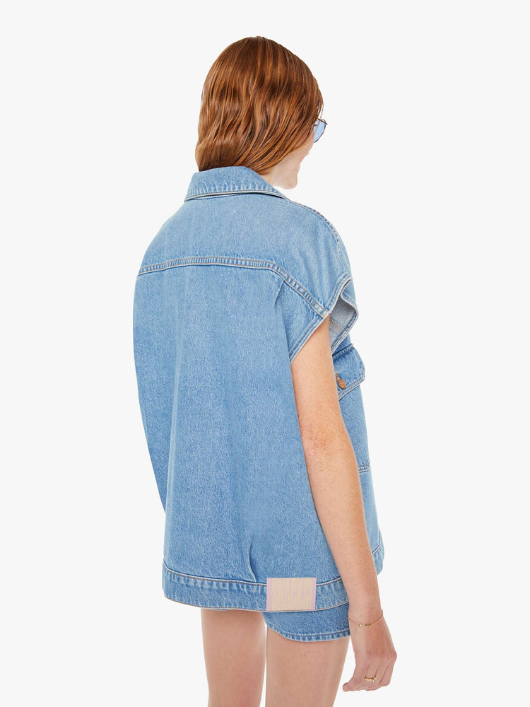Back view of a womens light blue denim vest featuring an oversized fit.