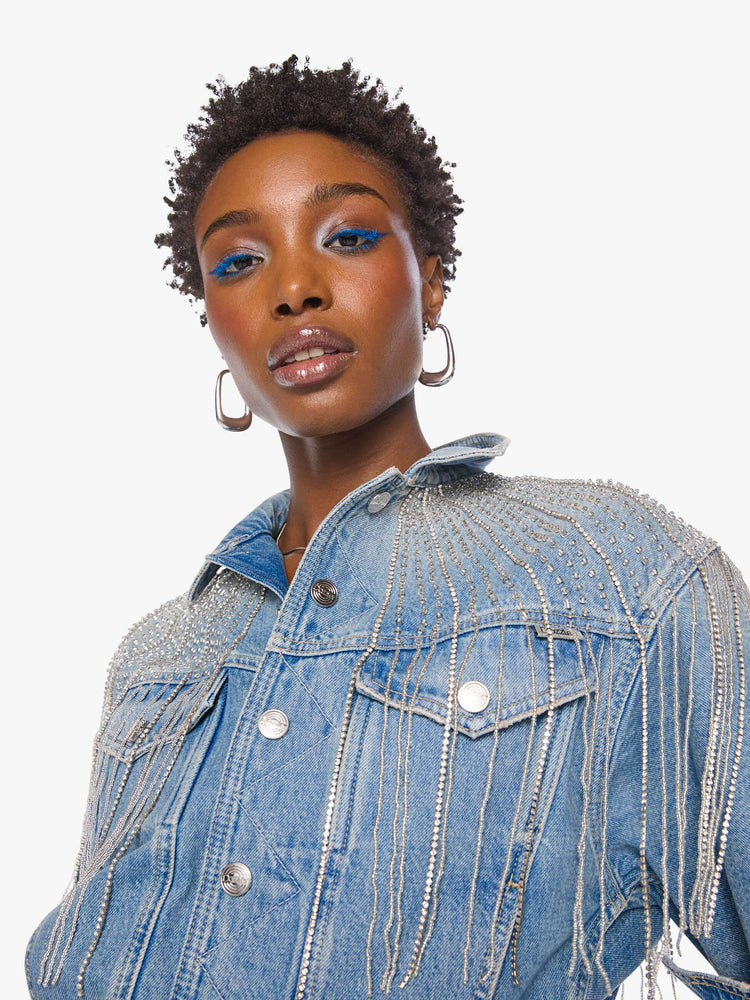 Close up view of a woman in a light blue  jacket with fading on the chest and elbows and glittery fringe around the neck.