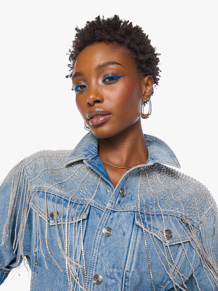 Close up view of a woman in a light blue  jacket with fading on the chest and elbows and glittery fringe around the neck.