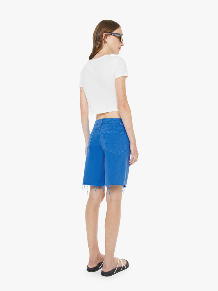 Back view of a woman in a primary blue wide-leg shorts with a high rise, zip fly and a 9-inch inseam with a frayed hem.