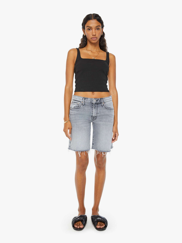 Front view of a woman in light-grey low-rise frayed hem denim shorts with whiskering and fading.