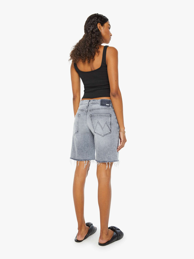 Back view of a woman in light-grey low-rise frayed hem denim shorts with whiskering and fading.