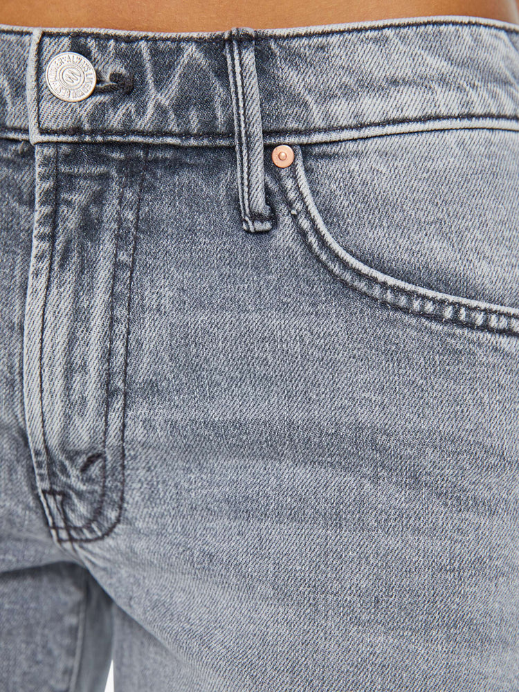 Detailed view of a woman in light-grey low-rise frayed hem denim shorts with whiskering and fading.