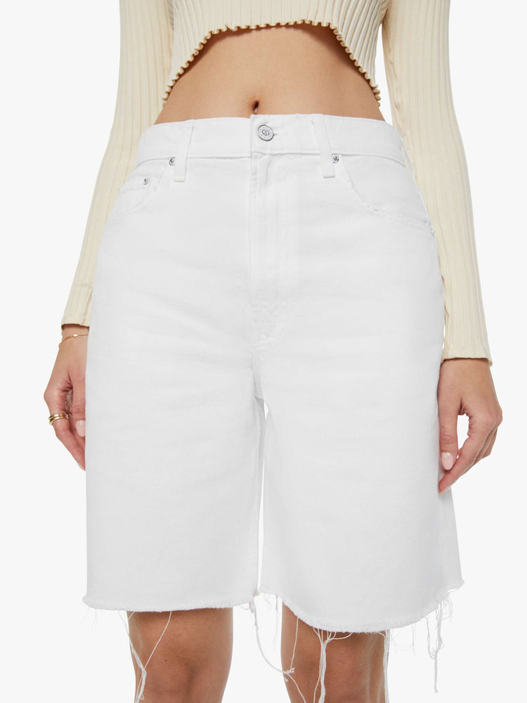 Detailed front view of a woman in off-white shorts that have a super-high rise, loose leg with a frayed hem and a pretzel-detailed button.