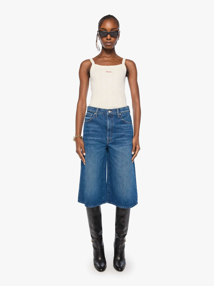 Front view of woman in med blue high-waisted shorts have a low-slung fit and feature a wide leg, zip fly, calf-length inseam and a clean hem.