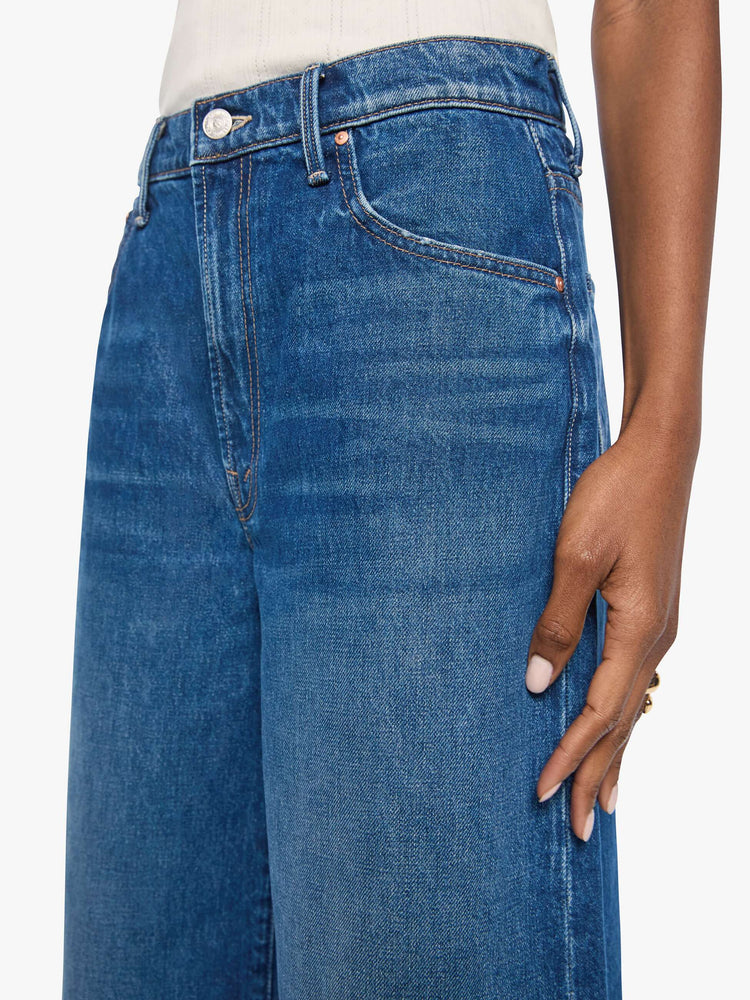 Close up view of woman in med blue high-waisted shorts have a low-slung fit and feature a wide leg, zip fly, calf-length inseam and a clean hem.
