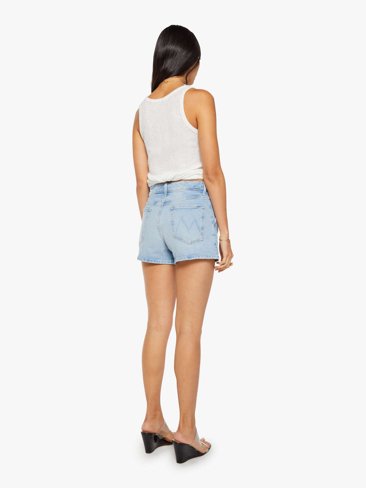 Back view of a woman in a light blue high-waisted denim shorts with a zip fly, slit pockets, pleats at the waistband and a 3-inch inseam with a clean hem.