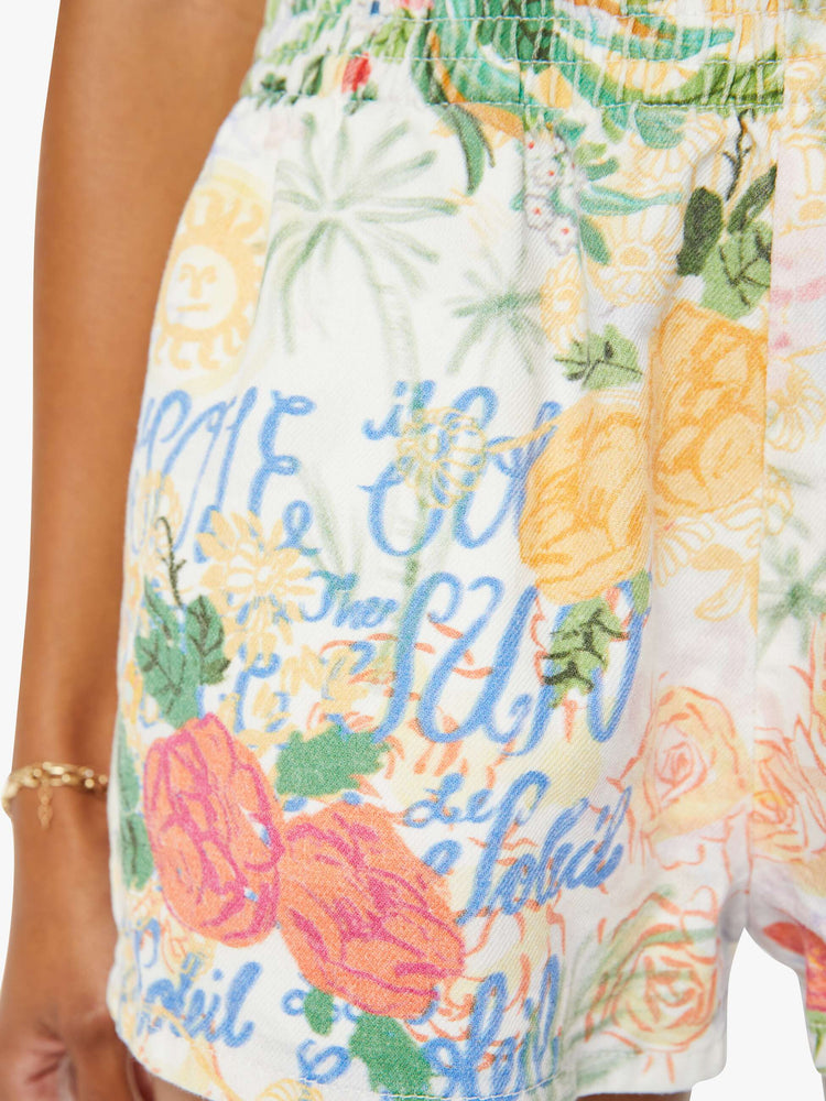 Detailed view of a woman in white high waisted pull on shorts with floral print.
