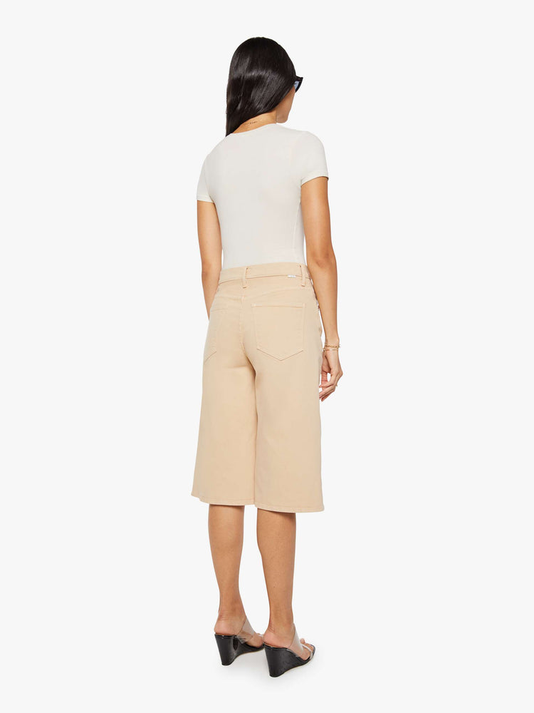 Back view of a woman in a khaki super high-waisted shorts with a wide leg, zip fly, calf-length inseam and a clean hem.