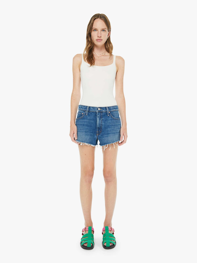 Front view of a woman in a classic blue shorts designed to sit lower on the hips with a loose leg, zip fly and 2.5-inch inseam with a frayed hem.