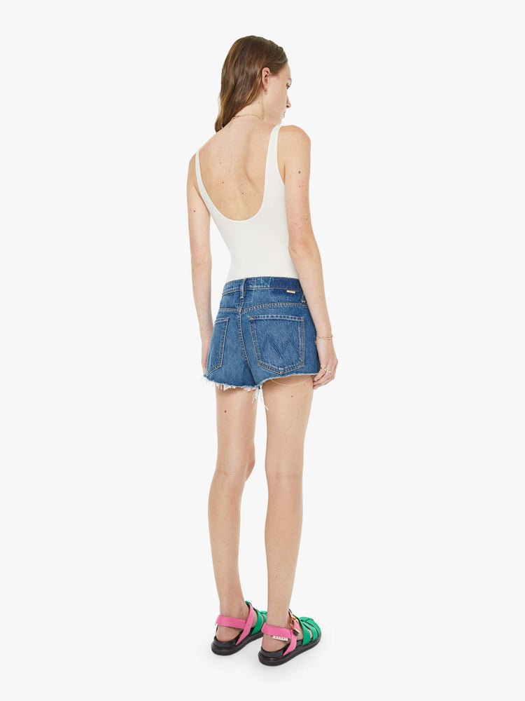 Back view of a woman in a classic blue shorts designed to sit lower on the hips with a loose leg, zip fly and 2.5-inch inseam with a frayed hem.