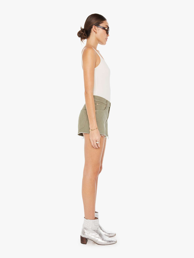 Side view of a greenish brown denim short featuring a relaxed mid rise and a short frayed hem.