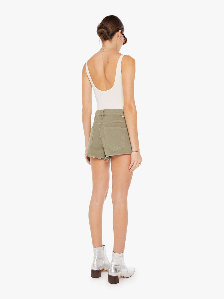 Back view of a greenish brown denim short featuring a relaxed mid rise and a short frayed hem.