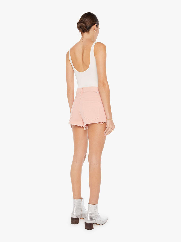 Back view of a faded pink denim short featuring a relaxed mid rise and a short frayed hem.