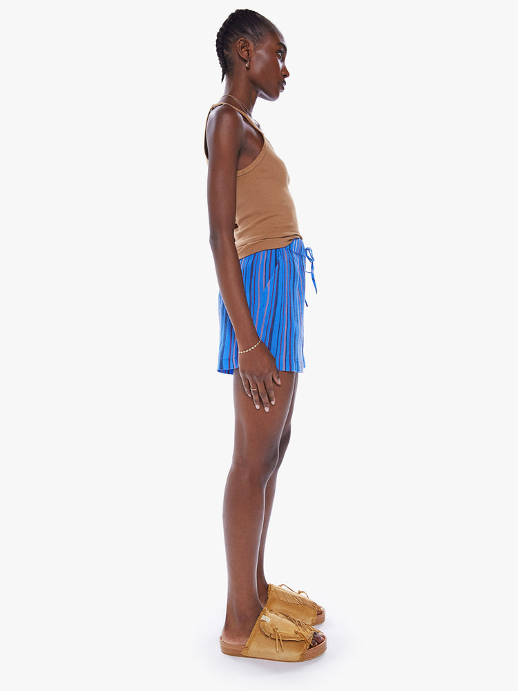 Side view of a woman high rise short, elastic drawstring waistband and side slit pockets in a blue stripe pattern.