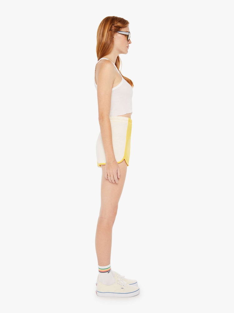 Side view of a womens yellow and white short featuring a high rise and elastic waist.