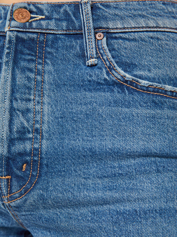 Swatch view of a woman in a mid blue high-waisted jean shorts with a button fly, 3-inch inseam and a frayed hem.