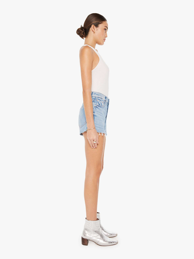 Side view of a womens light blue wash denim short featuring a high rise and a short frayed hem.
