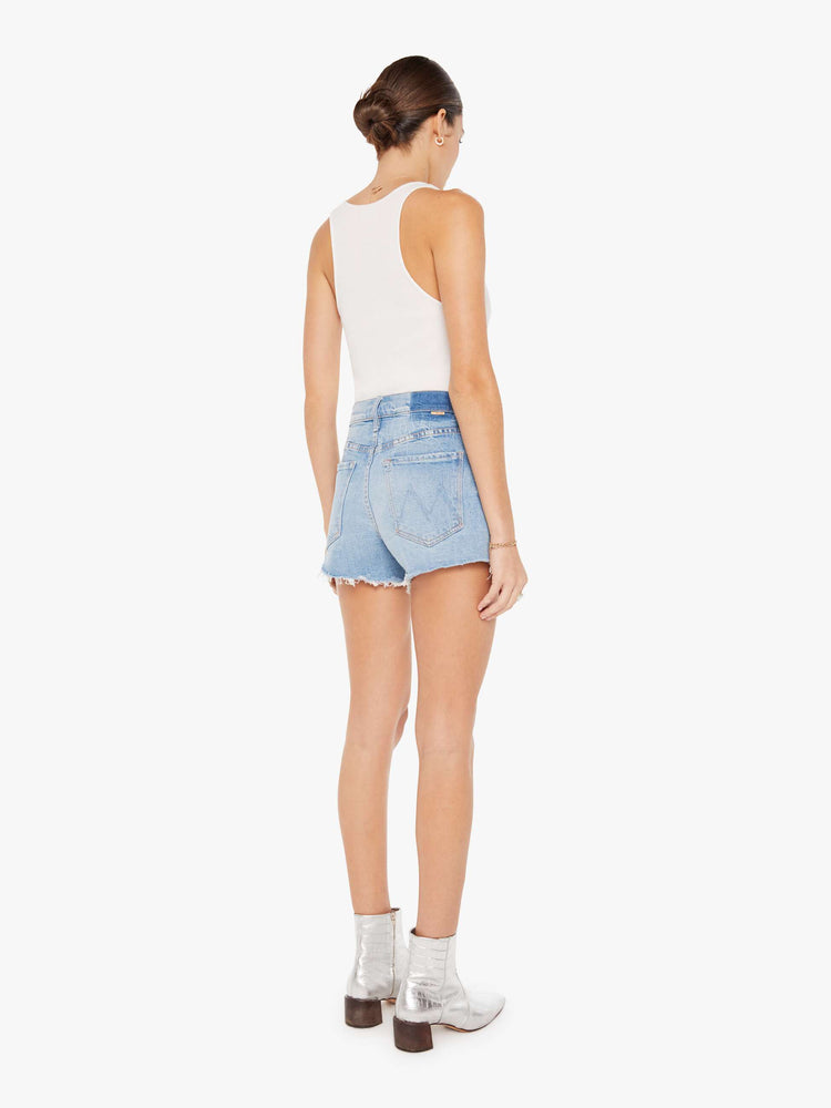 Back view of a womens light blue wash denim short featuring a high rise and a short frayed hem.