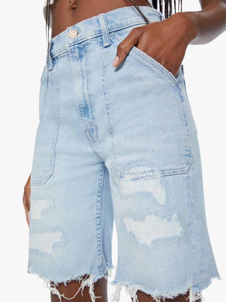Close up view of a woman light blue bermuda shorts with a high rise, oversized patch pockets, a 9-inch inseam and a raw hem.