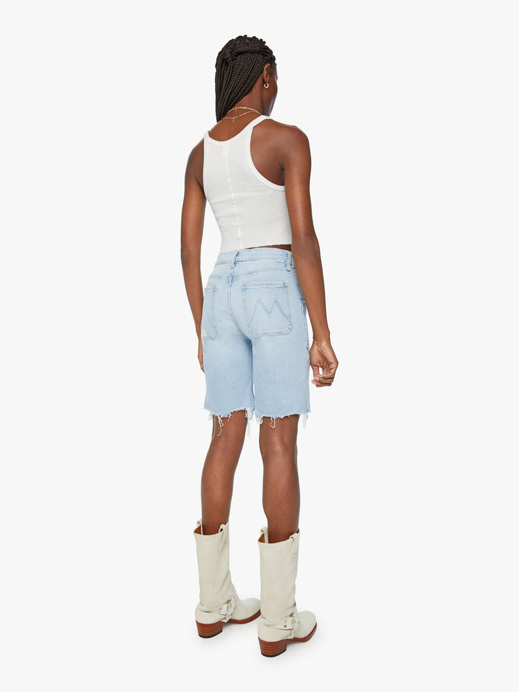 Back view of a woman light blue bermuda shorts with a high rise, oversized patch pockets, a 9-inch inseam and a raw hem.