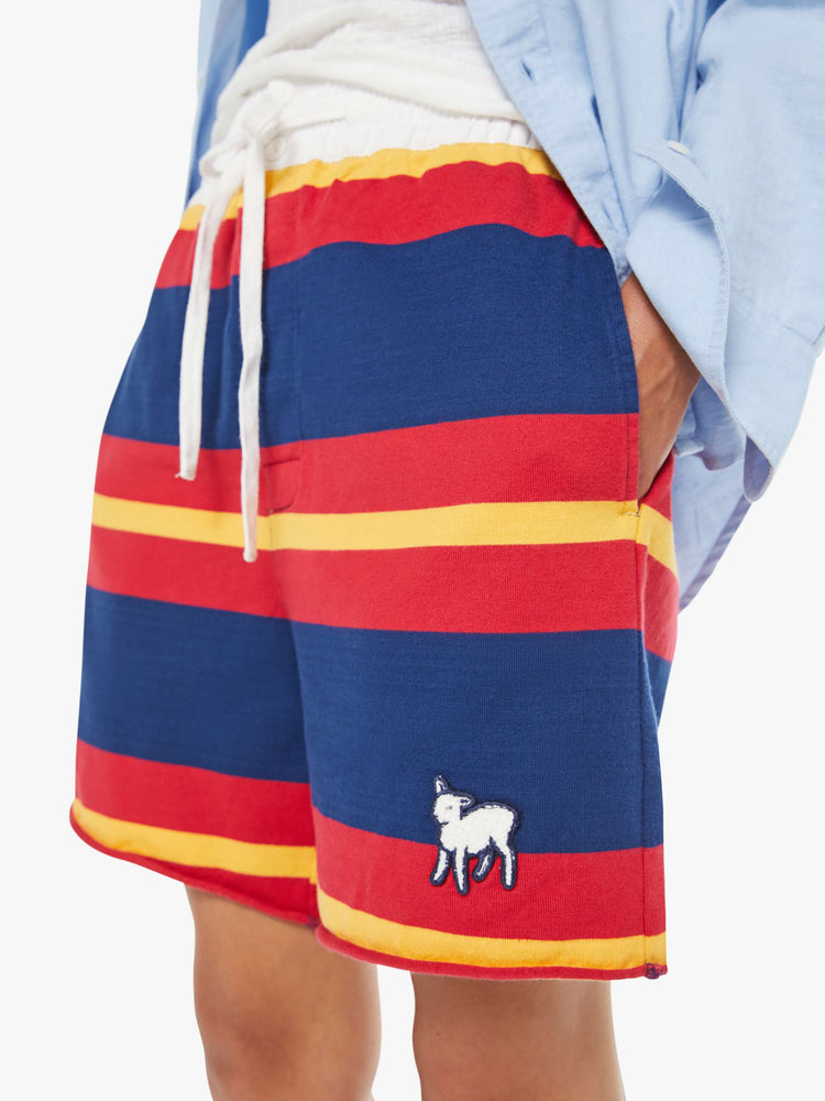Close up view of a woman in a shorts  with red, navy and golden-yellow stripes with a fuzzy lamb patch on the leg.