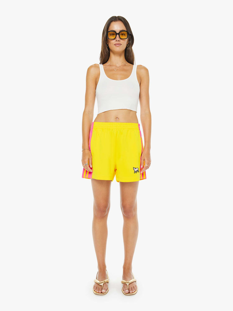 Front view of a woman in bright yellow athletic-inspired shorts with an elastic waistband and a loose leg.