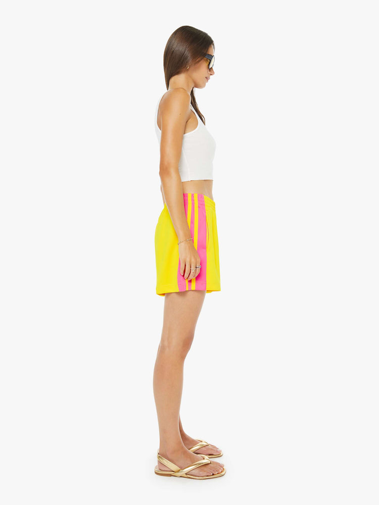 Side view of a woman in bright yellow athletic-inspired shorts with an elastic waistband and a loose leg.