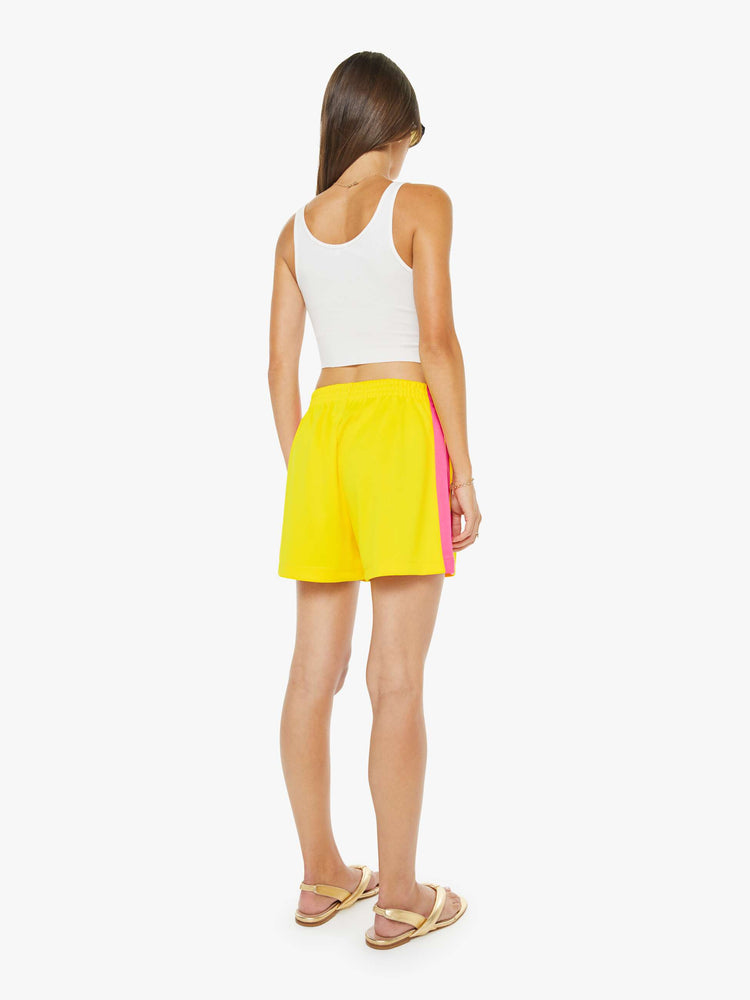 Back view of a woman in bright yellow athletic-inspired shorts with an elastic waistband and a loose leg.