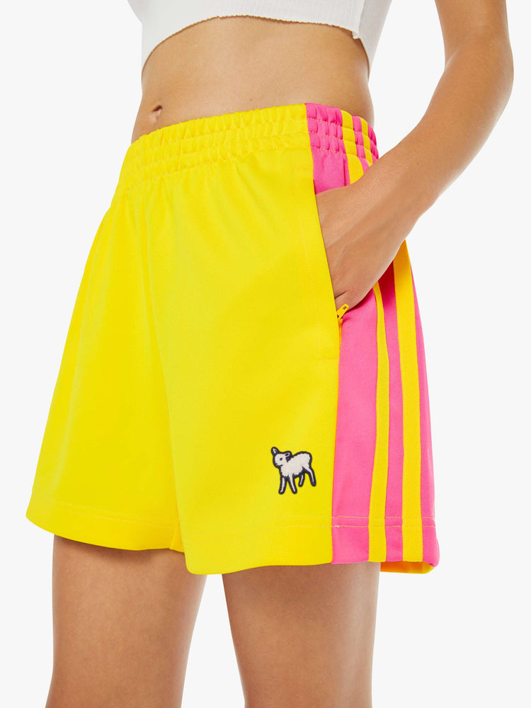 Close up view of a woman in bright yellow athletic-inspired shorts with an elastic waistband and a loose leg.