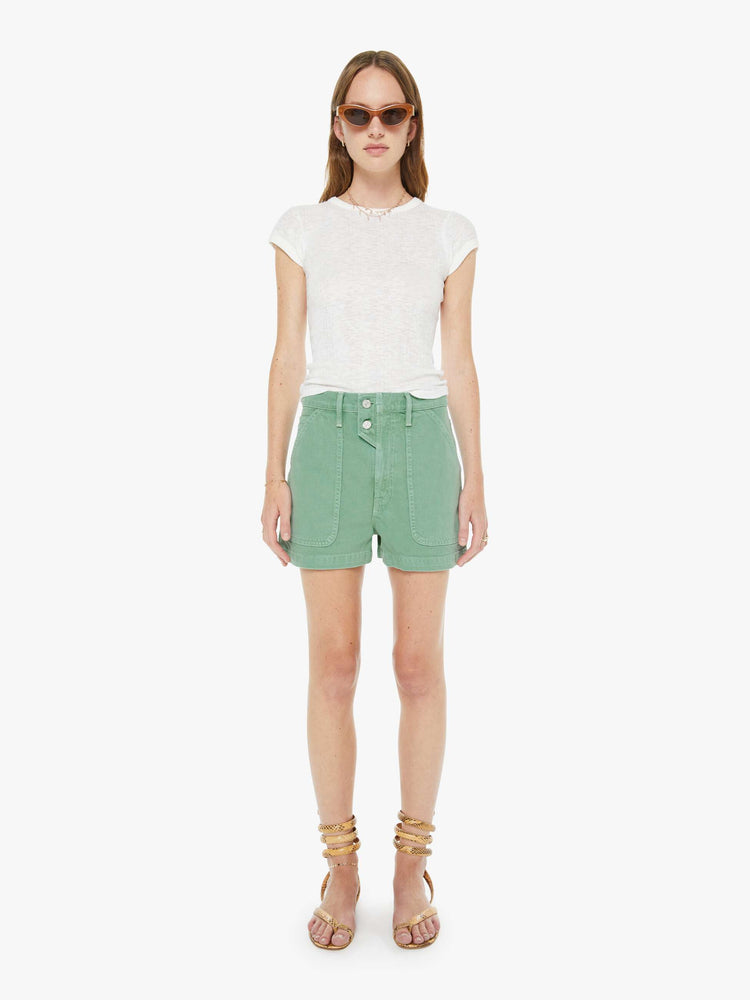 Front view of a woman in a faded sage green super high-waisted shorts with oversized patch pockets, a tabbed waistband with exposed buttons and a zip fly, a 2.75-inch inseam and a clean hem. 