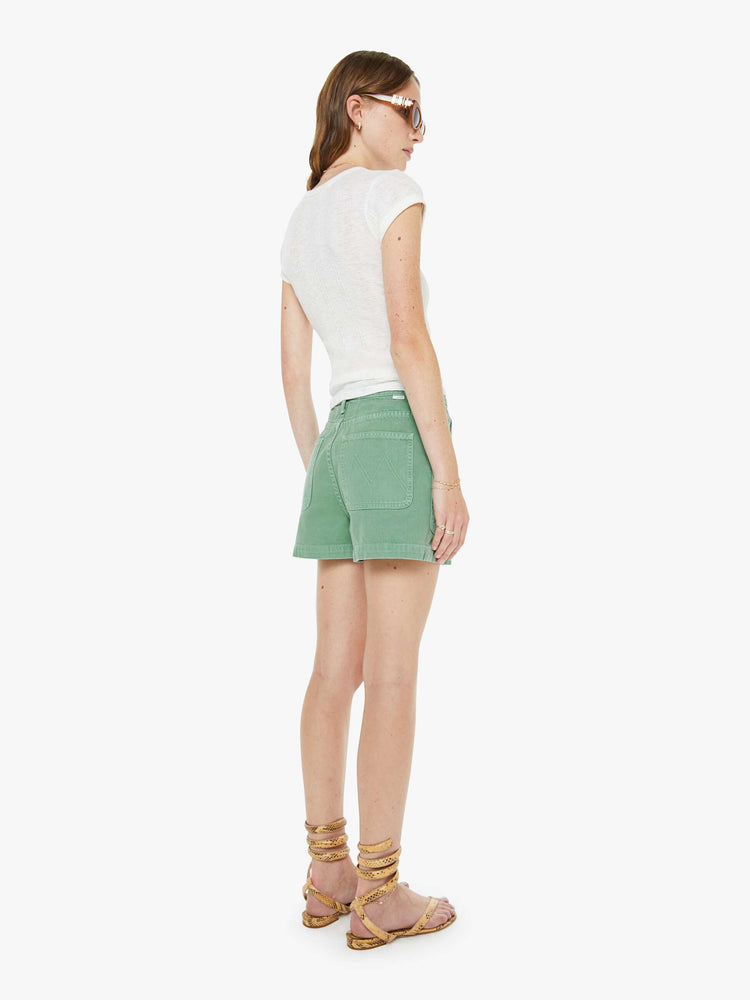 Back view of a woman in a faded sage green super high-waisted shorts with oversized patch pockets, a tabbed waistband with exposed buttons and a zip fly, a 2.75-inch inseam and a clean hem. 