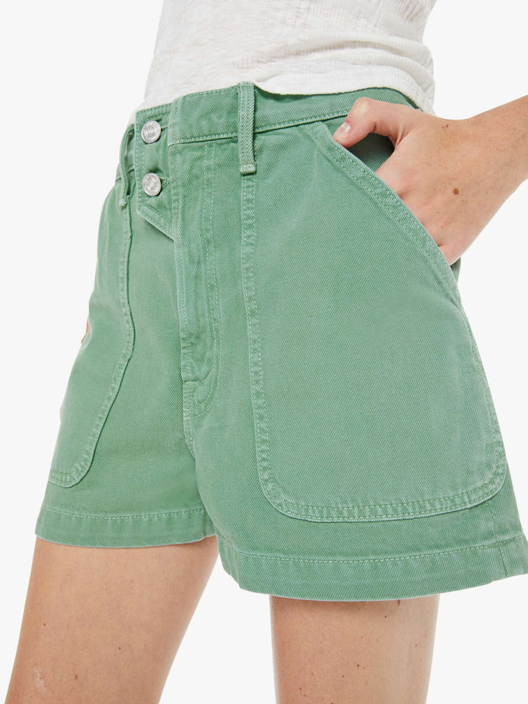 Close up view of a woman in a faded sage green super high-waisted shorts with oversized patch pockets, a tabbed waistband with exposed buttons and a zip fly, a 2.75-inch inseam and a clean hem. 